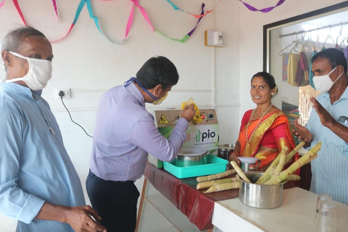 ZP CEO Dr Selvamani R inaugurates the solar-powered sugarcane juicer by inserting sugarcane for crushing inside the juicer, at Garadipalla, in Balepuni.