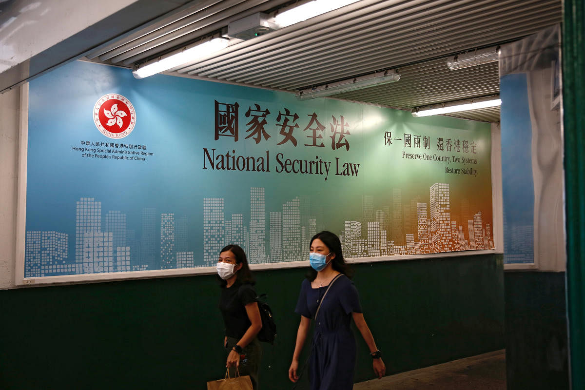 Women walk past a government-sponsored advertisement promoting the new national security law as a meeting on national security legislation takes place in in Hong Kong. Credit/Reuters Photo