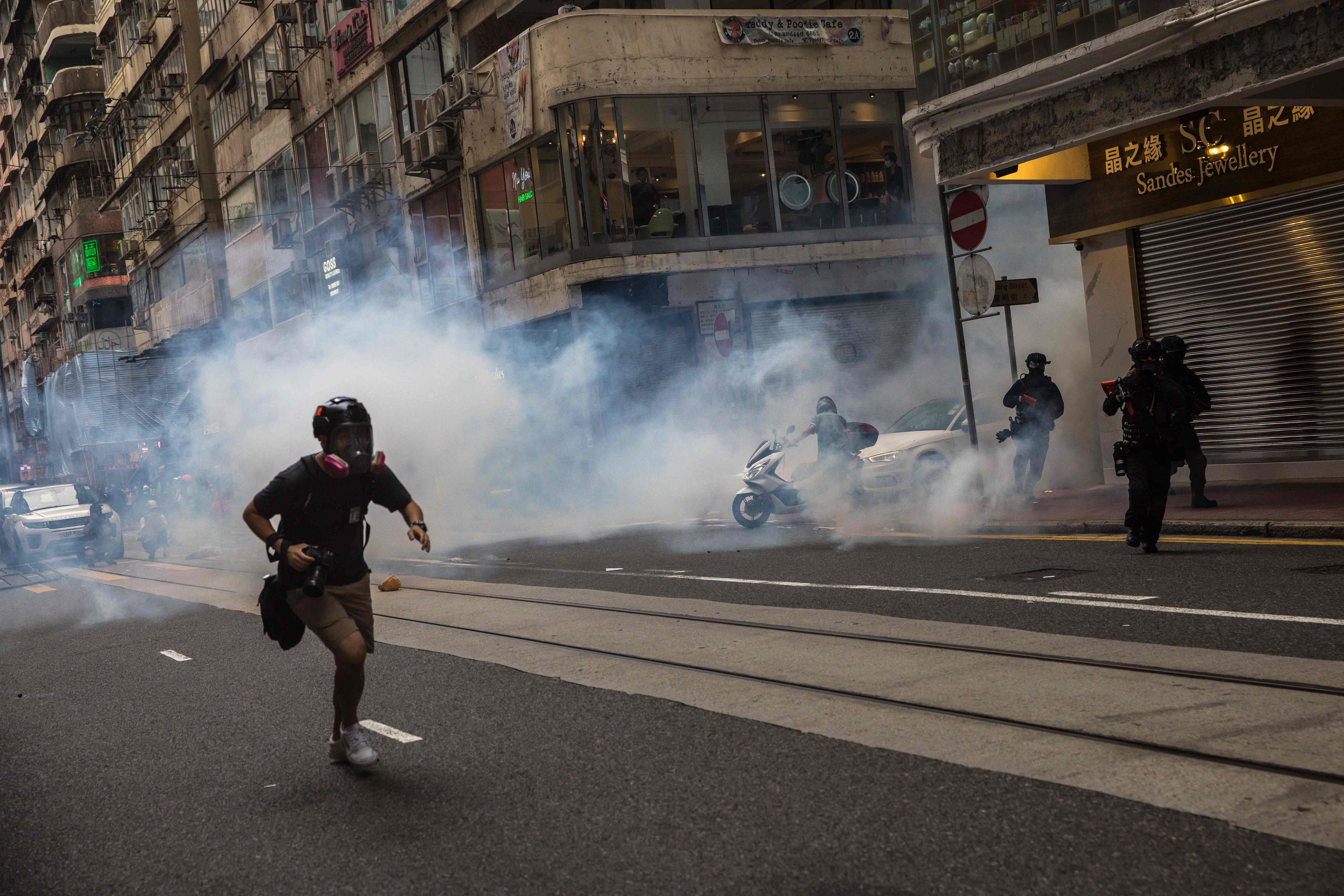 Riot police deploy tear gas as they clear protesters from a road during a rally against a new national security law in Hong Kong on July 1, 2020, on the 23rd anniversary of the city's handover from Britain to China. - Hong Kong police made the first arrests under Beijing's new national security law on July 1 as the city greeted the anniversary of its handover to China with protesters fleeing water cannon. (Photo by AFP)