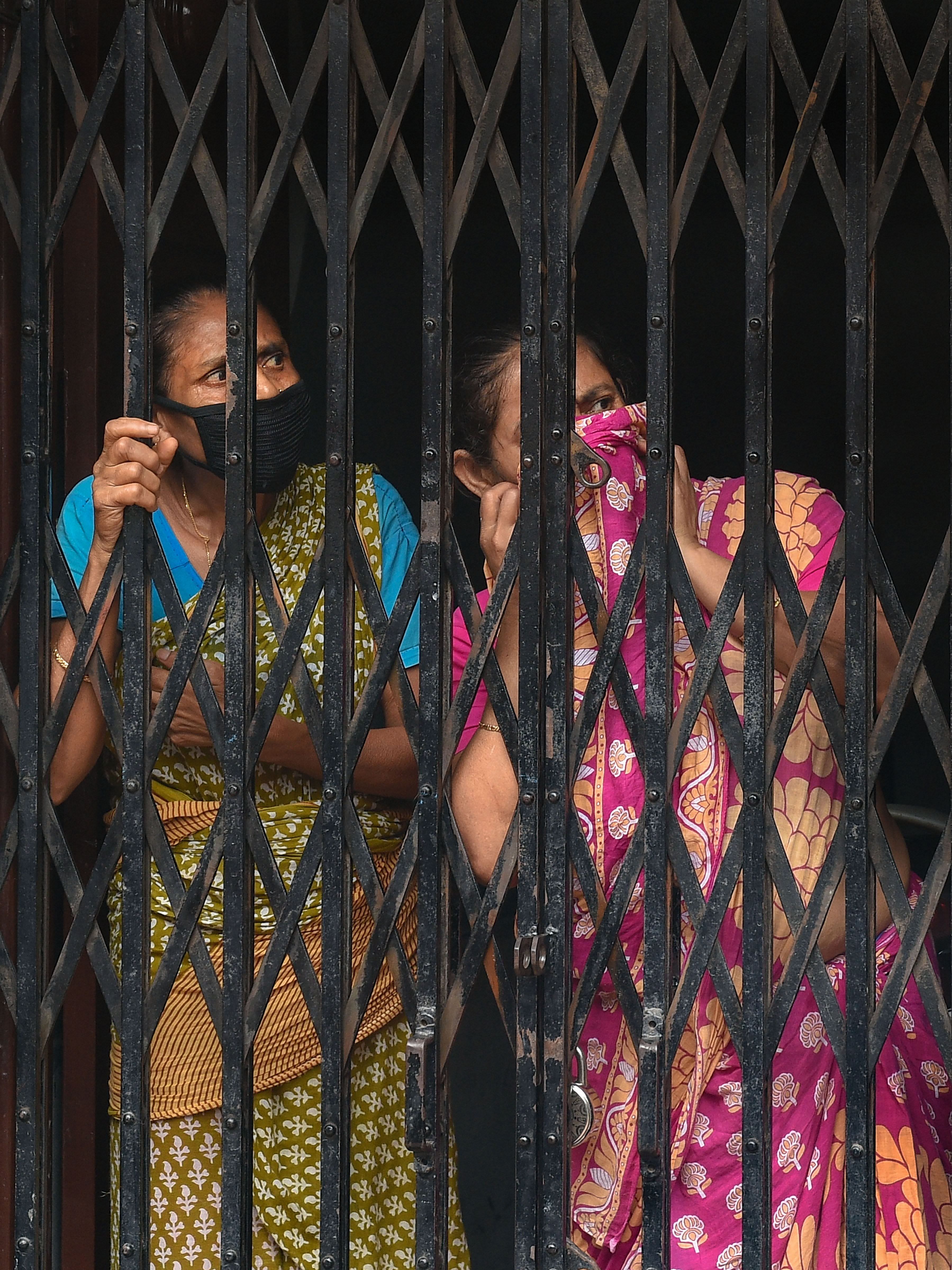 Neighbours look on as KMC workers transport a 71-year-old COVID-19 victim from his residence, in Kolkata, Wednesday, July 1, 2020. (PTI Photo)