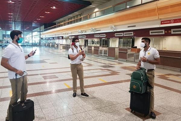 In this handout picture released and taken by Pakistan Cricket Board (PCB) on June 28, 2020, Pakistani cricketers Babar Azam (R), Imad Wasim (L) and Imam-ul-Haq (C) wearing facemasks arrive at the Allama Iqbal International airport before their departure to England, in Lahore. Credit: AFP Photo