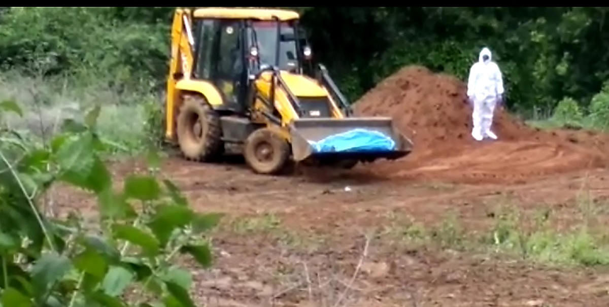 The body of 56-year old Covid 19-victim buried in Channagiri using earth mover. DH Photo