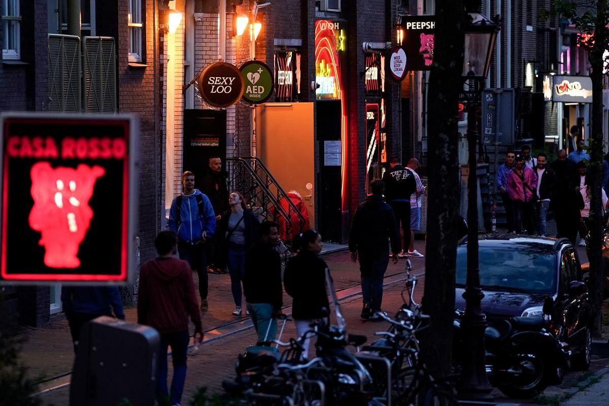 People walk along a street of the red light district in Amsterdam on July 1, 2020, as Dutch brothels reopened today after a long coronavirus shutdown, with sex workers and clients having to observe new rules to prevent Covid-19 infection. Credit/AFP Photo