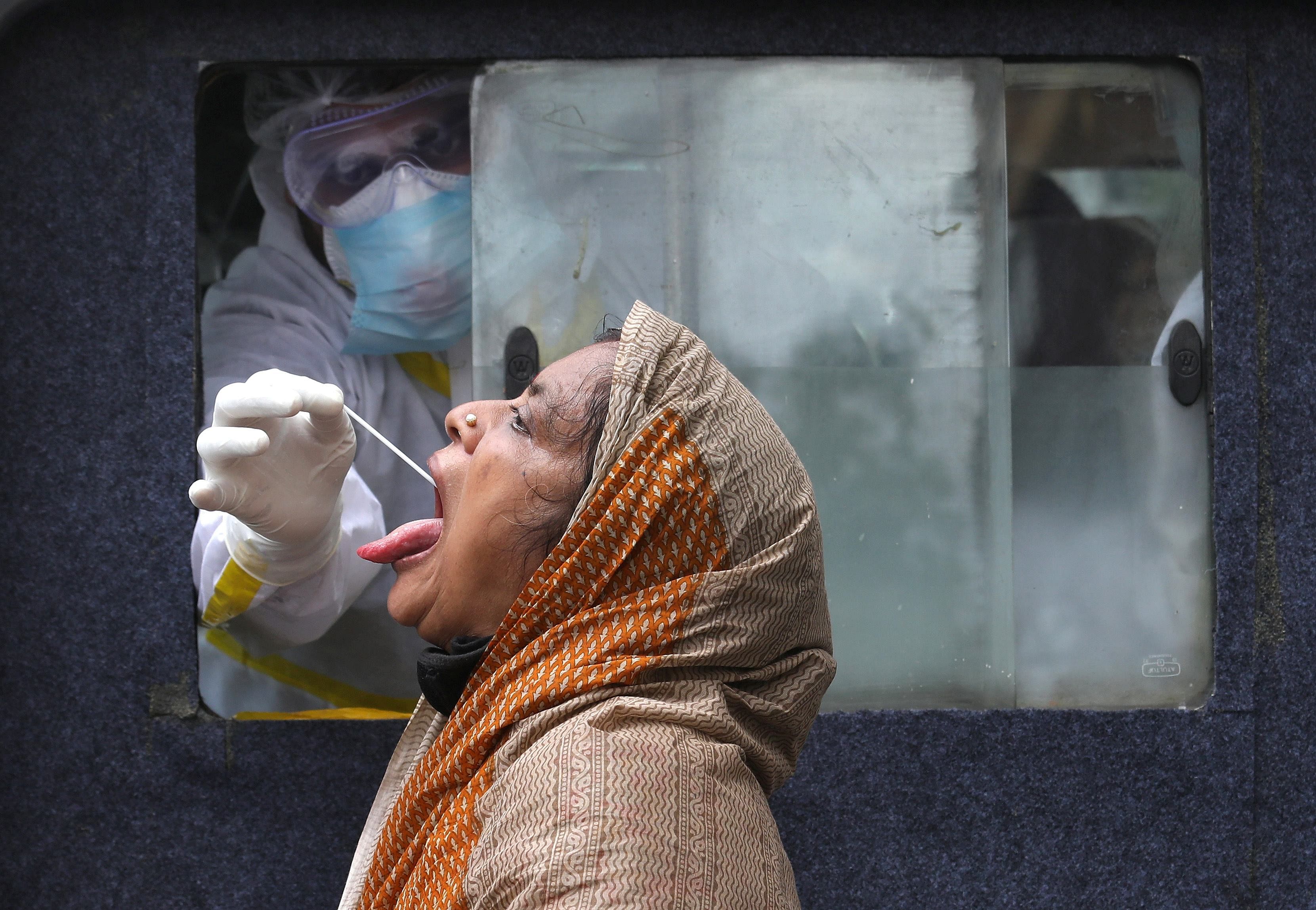 A woman reacts as a healthcare worker sitting inside an ambulance takes a swab from her to test for the coronavirus disease (COVID-19) in Kolkata. Credit: Reuters
