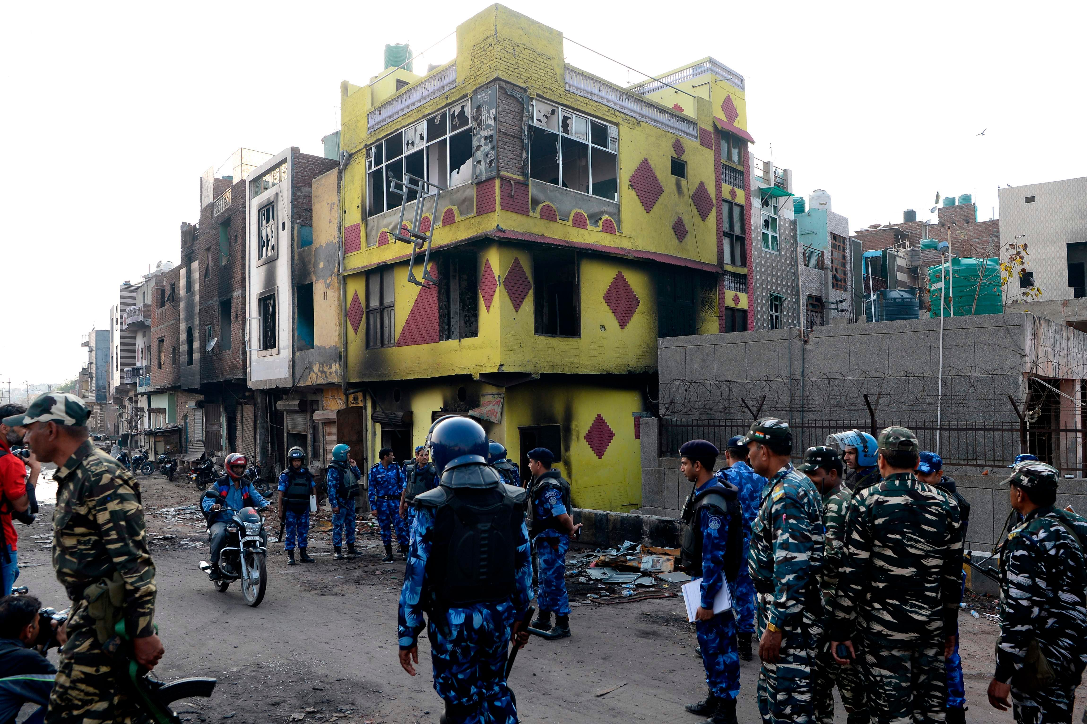 Police patrol a road near a partially burnt down building in a riot-affected area, in New Delhi. Credits: AFP Photo
