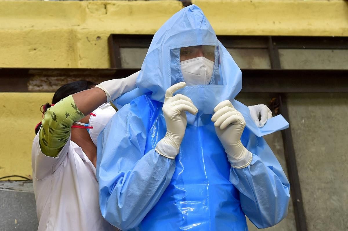 A medic helps her collegue wear a PPE before collecting samples for COVID-19 swab testing at Halasuru Gate traffic police station, during Unlock 2.0, in Bengaluru, Wednesday, July 1, 2020. (PTI Photo)