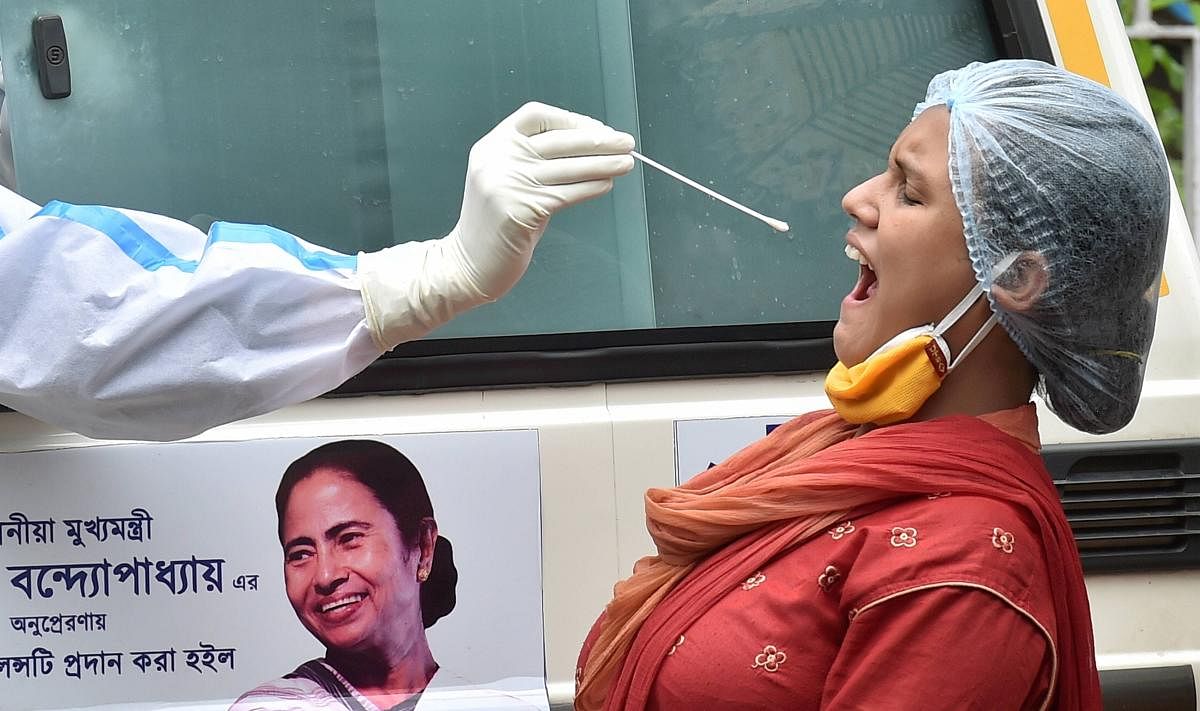 A health worker collects swab sample of a woman from an ambulance for COVID-19 testing at a locality, during Unlock- 2:0, in Kolkata, Friday, July, 3, 2020. (PTI Photo)