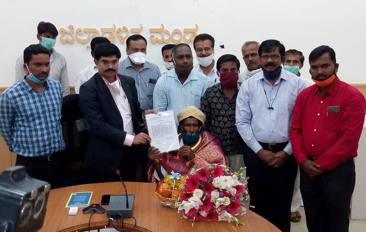 Deputy Commissioner Dr M V Venkatesh felicitates Malavalli farmer Dasanadoddi Kamegowda, at a programme in Mandya on Friday. DH PHOTO