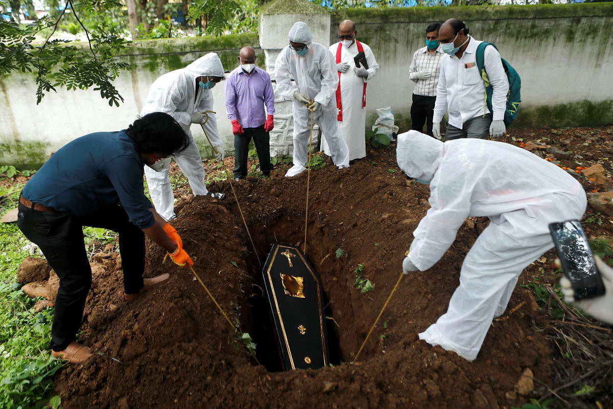 People lower the coffin of a victim who died from the coronavirus disease (COVID-19) into a grave at a cemetery as a priest and relative watch, during a funeral in Mumbai, India, June 23, 2020. Credit/Reuters Photo