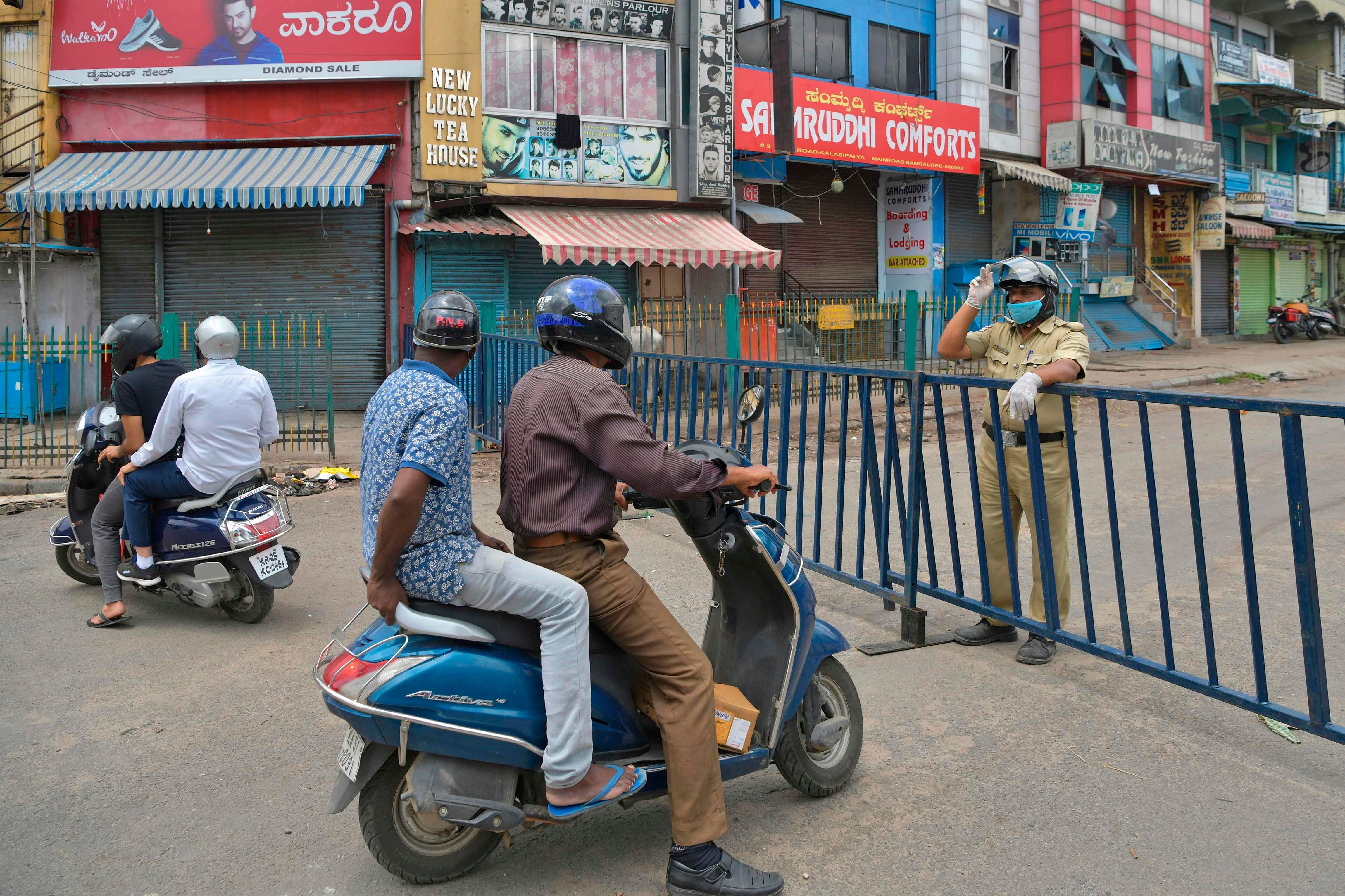 A policeman sends motorists back as he stands guard near a barricaded commercial street lined with shops and business establishments, which was closed by the authorities in Bengaluru as coronavirus cases continue to rise.. (Photo by AFP)