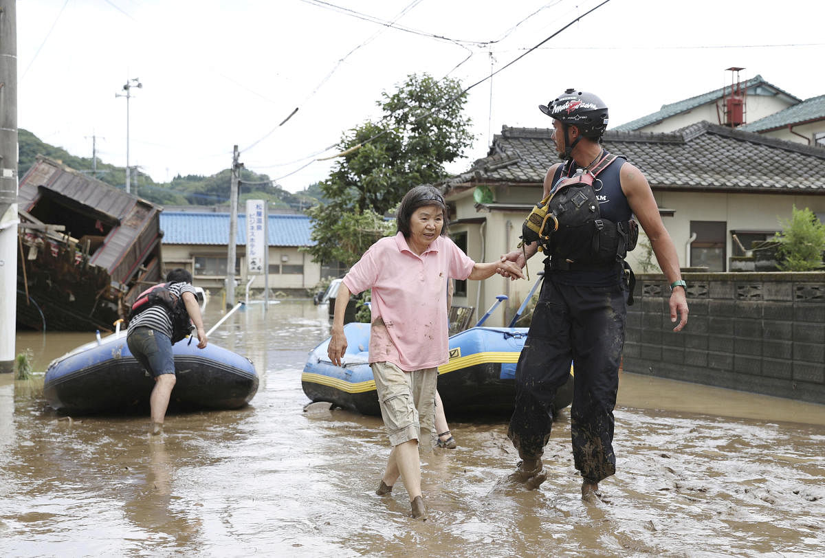 A rescue worker helps local residents at a flooded area caused by a heavy rain along Kuma River in Hitoyoshi, Kumamoto prefecture, southern Japan, in this photo taken by Kyodo July 4, 2020. Credit Kyodo/via REUTERS