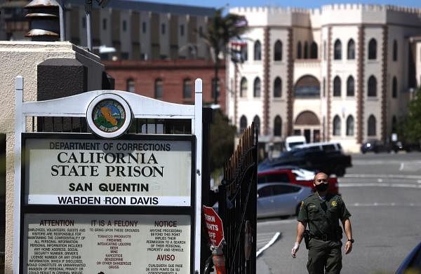 California Department of Corrections and Rehabilitation (CDCR) officer wears a protective mask as he stands guard at the front gate of San Quentin State Prison in San Quentin, California. Credit: AFP Photo