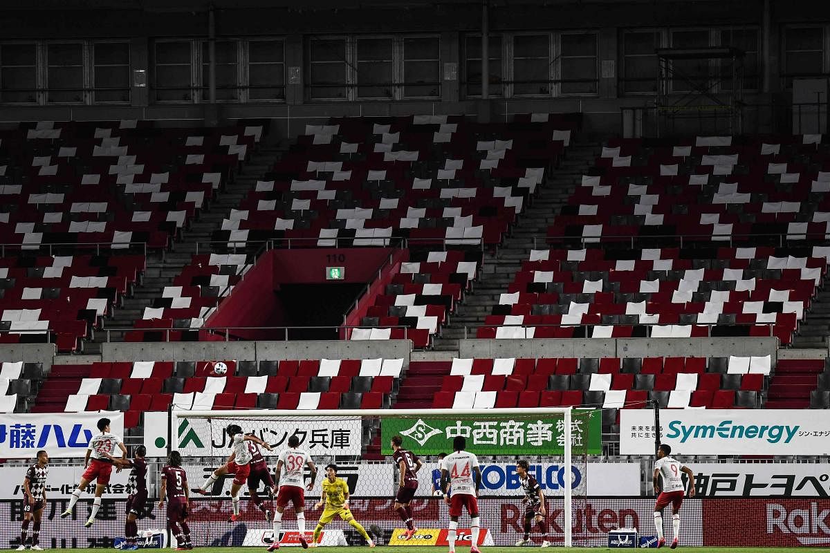 Players vie for the ball in an empty stadium during the J-League match between Vissel Kobe and Sanfrecce Hiroshima (white shirts) in Kobe. Credit: AFP
