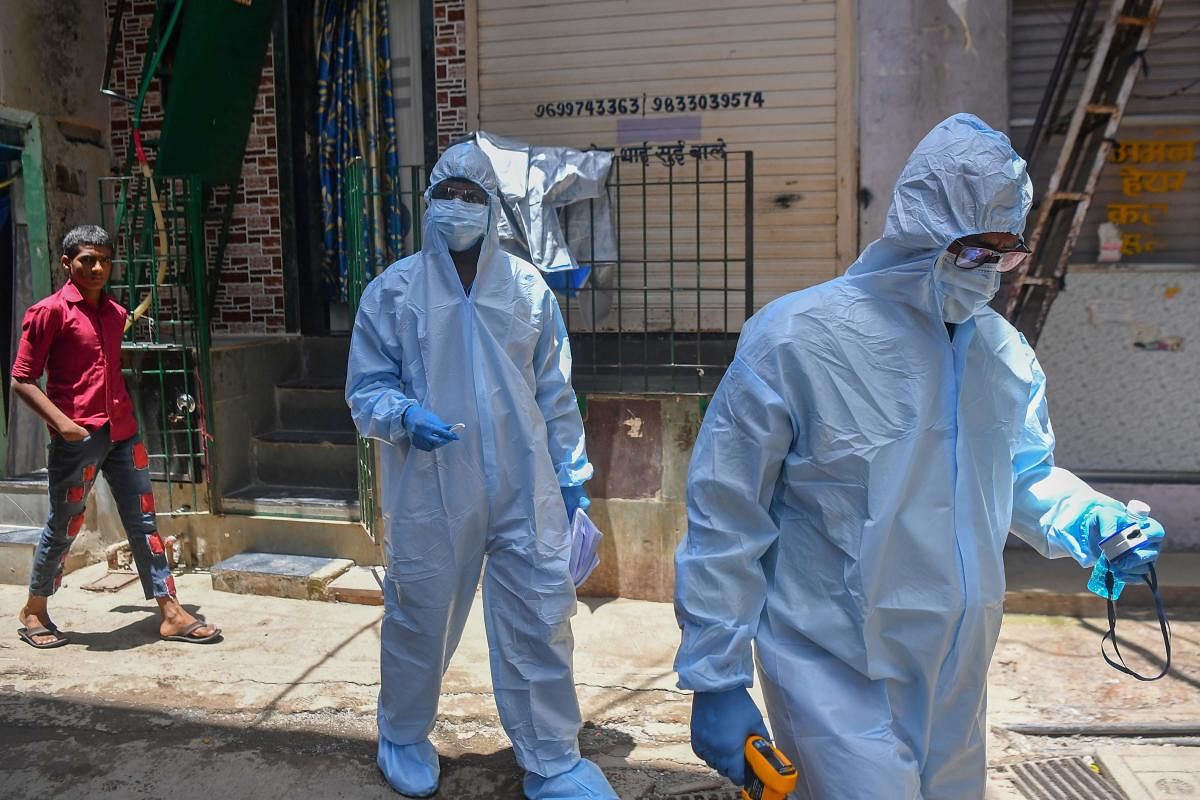 In this picture taken on June 24, 2020, medical staff wearing personal protective equipment (PPE) walk through a lane as they conduct a door-to-door medical screening inside the Dharavi slums to fight against the spread of the Covid-19 coronavirus in Mumbai. AFP