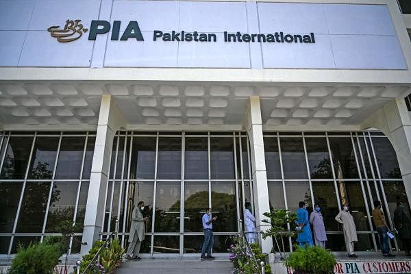 People stand in queue as they wait their turn to buy flight tickets outside Pakistan International Airlines (PIA) office in Islamabad on July 1, 2020. Credit: AFP Photo