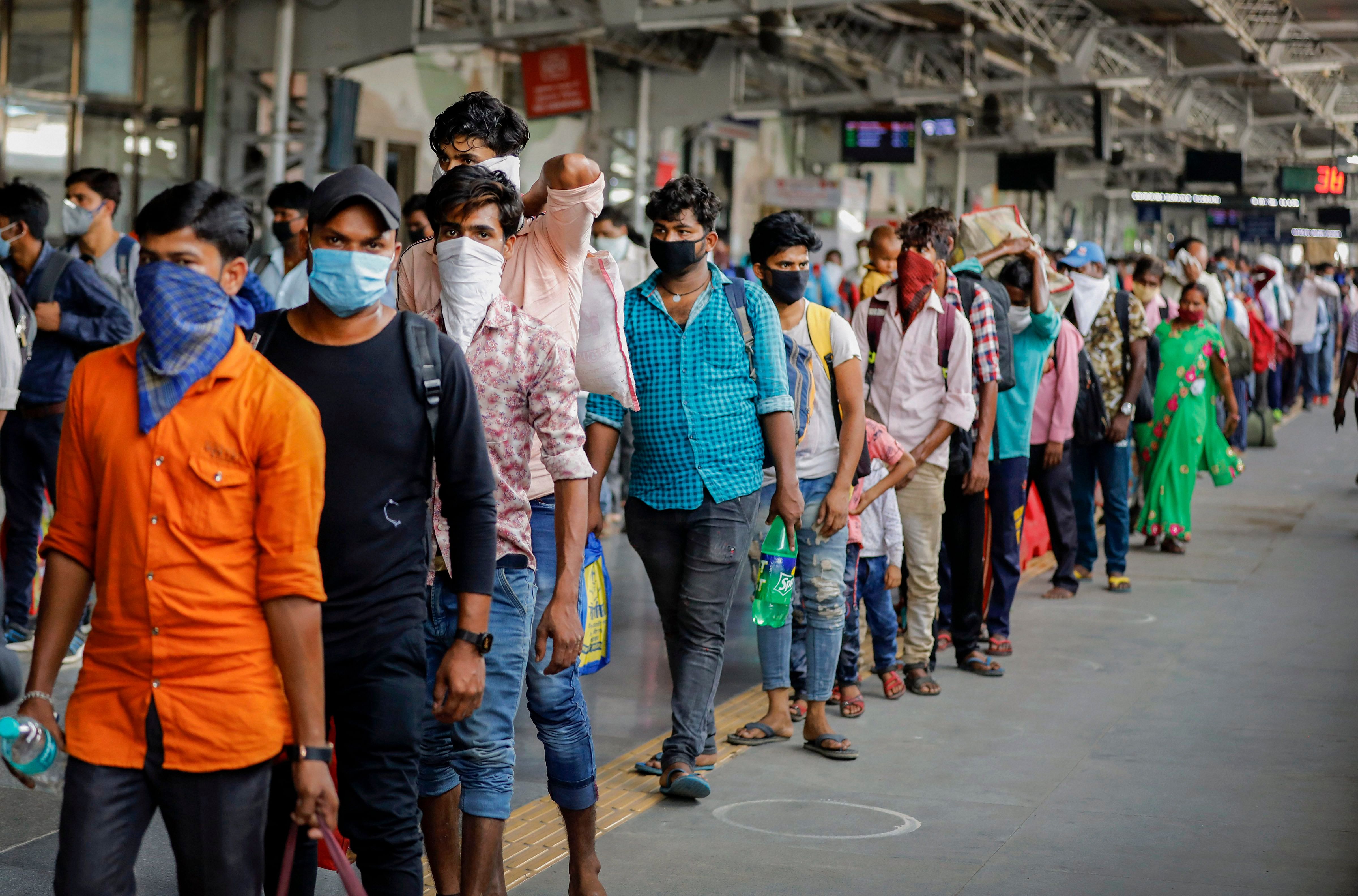 Migrant workers and their families, who had left for their hometown in UP during the nationwide lockdown, queue for screening on their return as they arrive at a railway station in Ahmedabad. (PTI Photo)