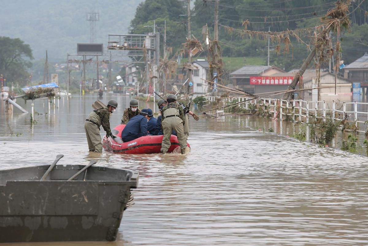 Japan Self-Defense Forces and police officers handle an inflatable boat to join rescue operations at a nursing home following heavy rain in Kuma village, Kumamoto prefecture. AFP