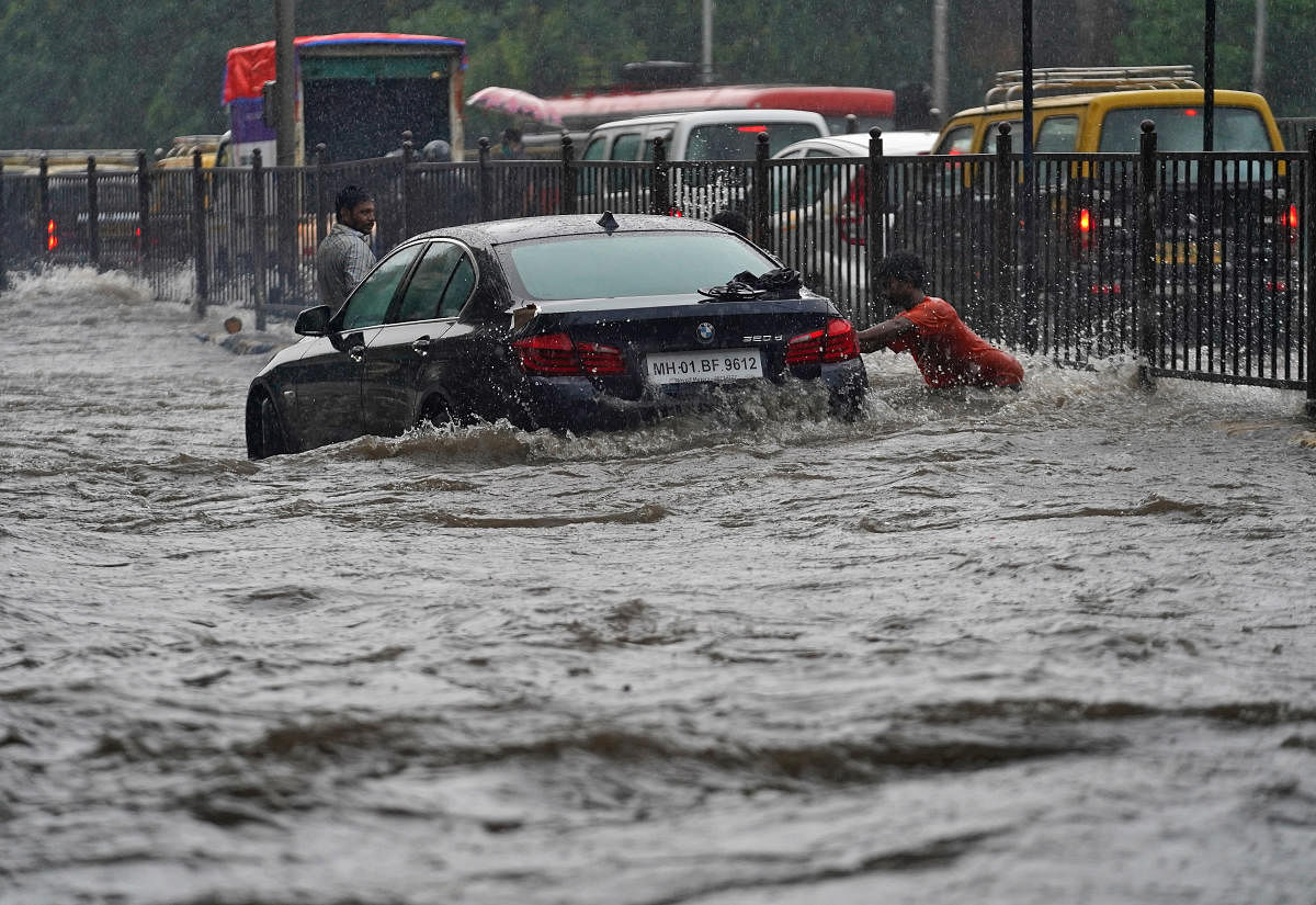 A man pushes a car, stuck in a flooded road, during heavy rains in Mumbai, India, July 4, 2020. Credit/Reuters Photo