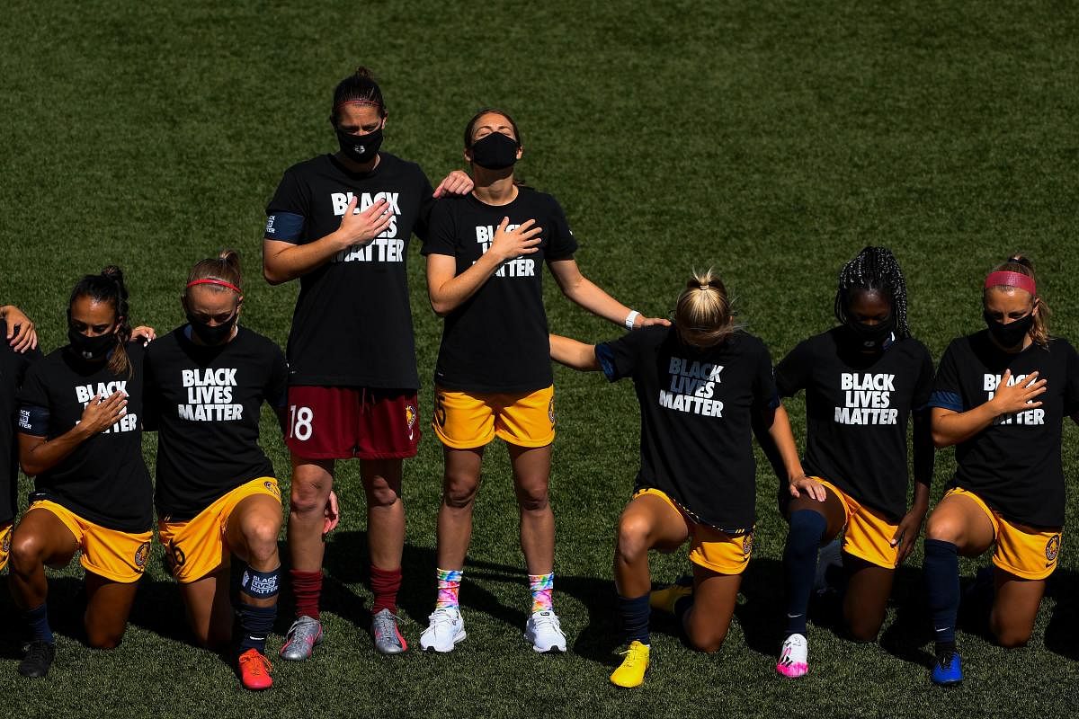 Nicole Barnhart #18 and Kelley O'Hara #5 of Utah Royals FC stand as teammates kneel for the national anthem before a game against the Sky Blue FC on day 4 of the NWSL Challenge Cup at Zions Bank Stadium on July 4, 2020 in Herriman, Utah. Alex Goodlett/Getty Images/AFP