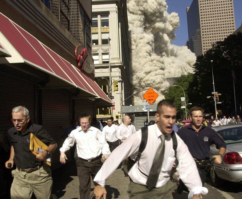 In this Sept. 11, 2001, file photo, people run from the collapse of one of the twin towers at the World Trade Center in New York. Stephen Cooper, far left, fleeing smoke and debris as the south tower crumbled just a block away on Sept. 11, has died from Covid-19, his family said. Credit: AP Photo/Suzanne Plunkett, File/apnews.com