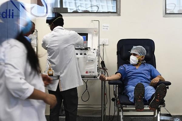 A plasma donor (R) is seen at the newly inaugurated plasma bank of the Institute of Liver and Biliary Sciences (ILBS) donating plasma for the treatment of patients suffering from the COVID-19 coronavirus, in New Delhi on July 2, 2020. Credits: AFP Photo