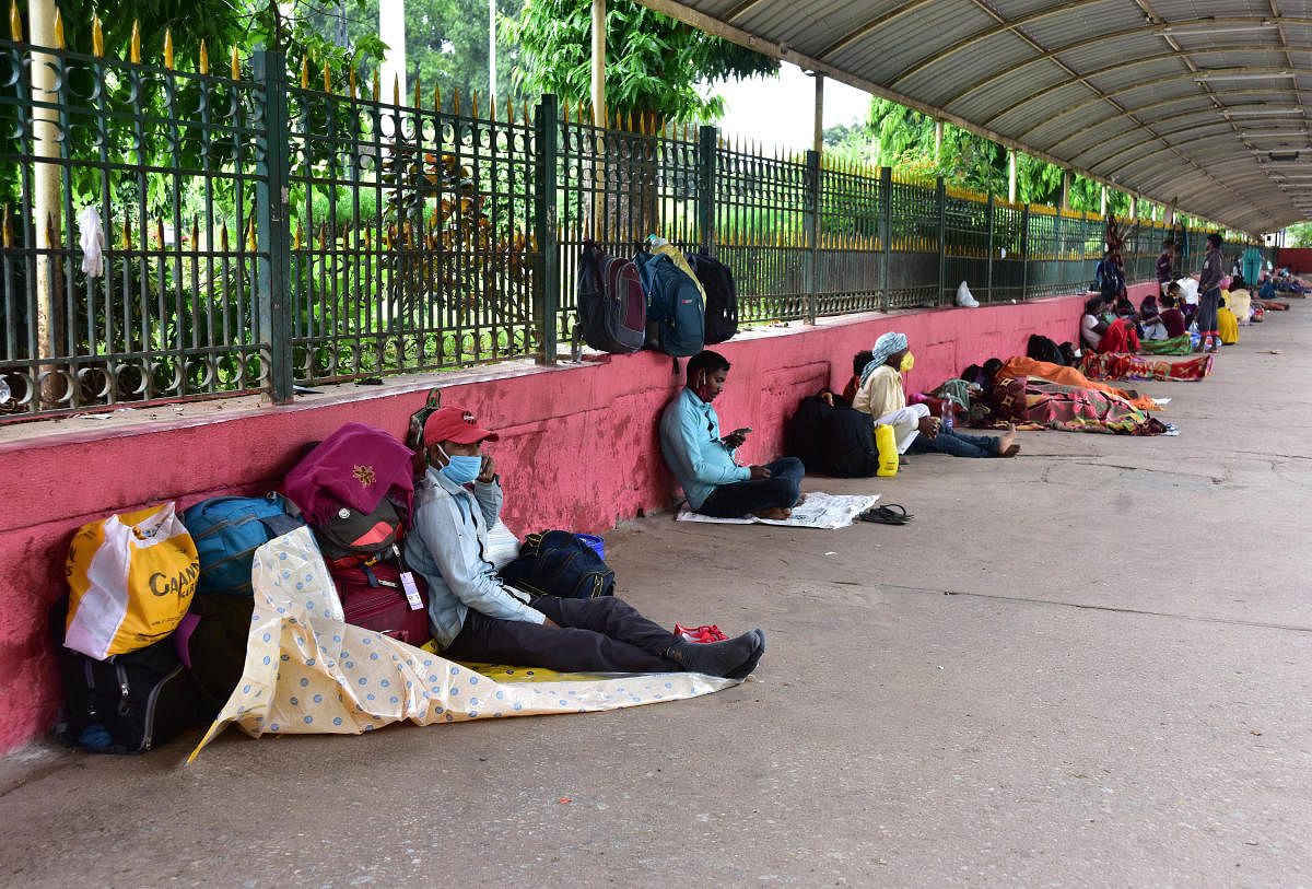 Passengers sit at KSR Railway Station premises on Sunday, waiting for a ride home. DH photo/Irshad Mahammad