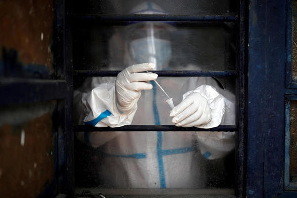 A health worker in personal protective equipment (PPE) puts a swab sample into a vial at a school which was turned into a centre to conduct tests for the coronavirus disease (COVID-19), amid the spread of the disease, in New Delhi, India July 4, 2020. Credit: Reuters Photo