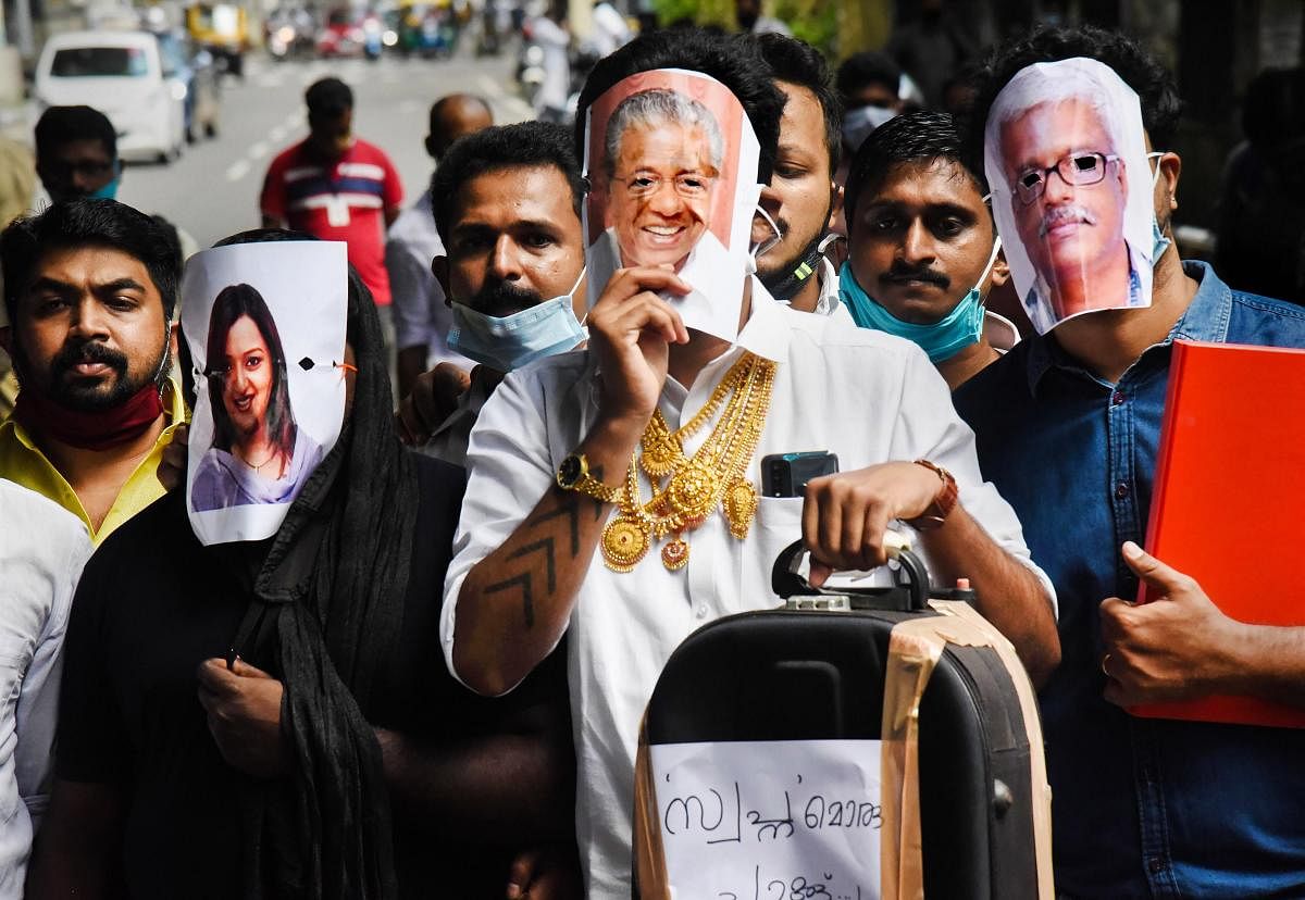 Youth Congress activists hold pictures of Kerala Chief Minister Pinarayi Vijayan (C), former UAE consulate officer Swapna Suresh (L), and State IT Secretary M Sivasankar (R) during a protest over the Kerala gold smuggling case, in Kochi, Credit: PTI Photo