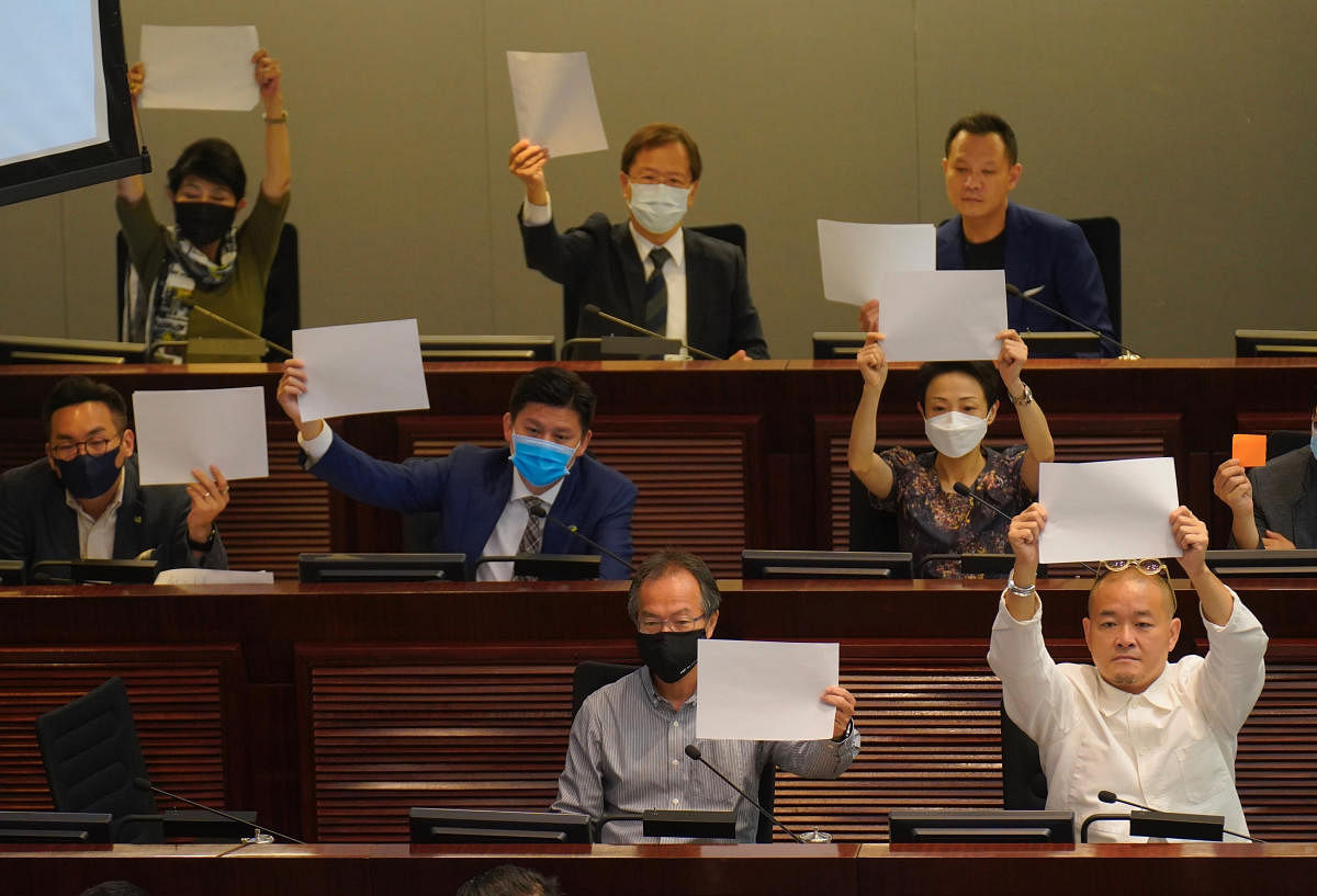  Pro-democracy lawmakers raise white papers to protest during a meeting to discuss the new national security law at the Legislative Council in Hong Kong (AP Photo)