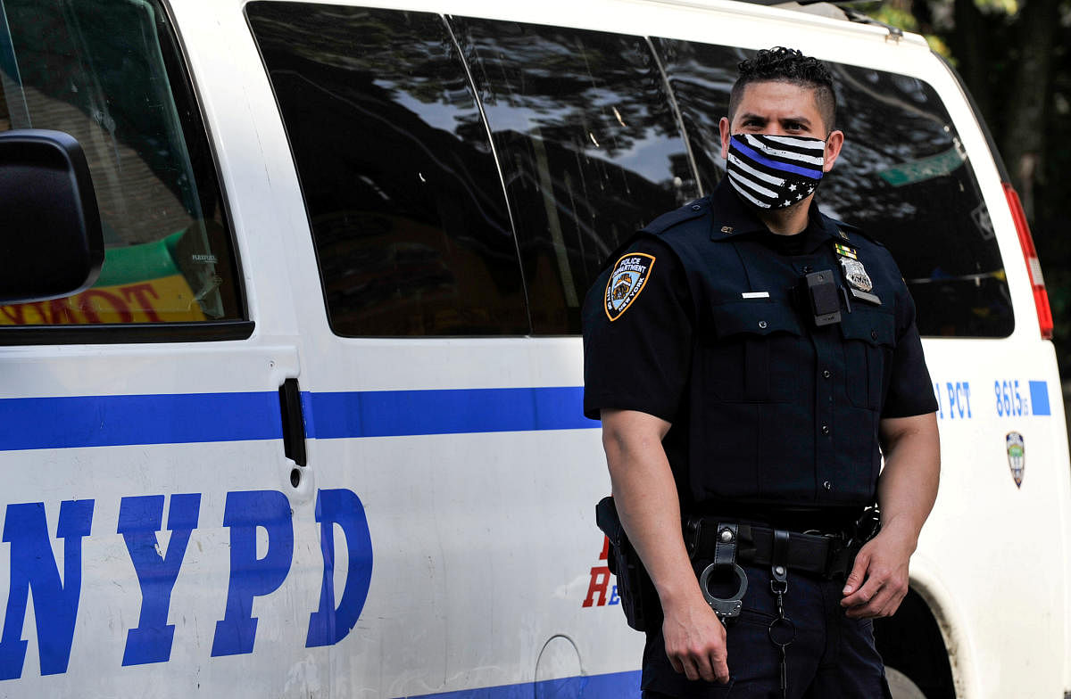A NYPD police offer wears a Blue Line face mask indicating support for law enforcement at the scene of a shooting in the Brooklyn borough of New York City. Credit: Reuters