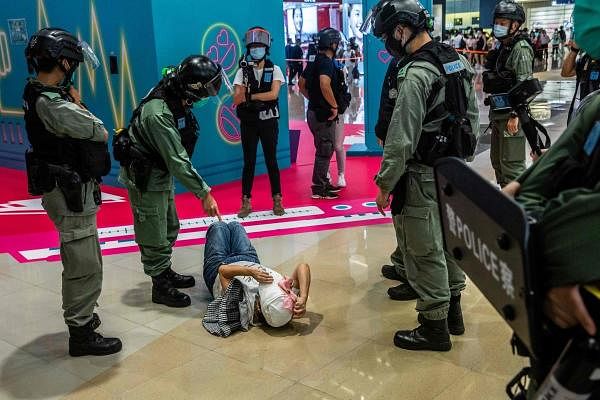 A riot police officer (2L) points at a woman (C) laying down after being searched during a demonstration in a mall in Hong Kong on July 6, 2020, in response to a new national security law introduced in the city which makes political views, slogans and signs advocating Hong Kong’s independence or liberation illegal. Credits: AFP Photo