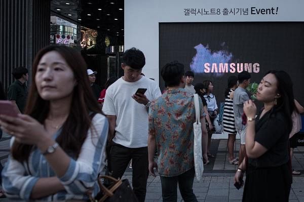 Pedestrians passing a Samsung promotional event outside a store in Seoul. Credits: AFP Photo
