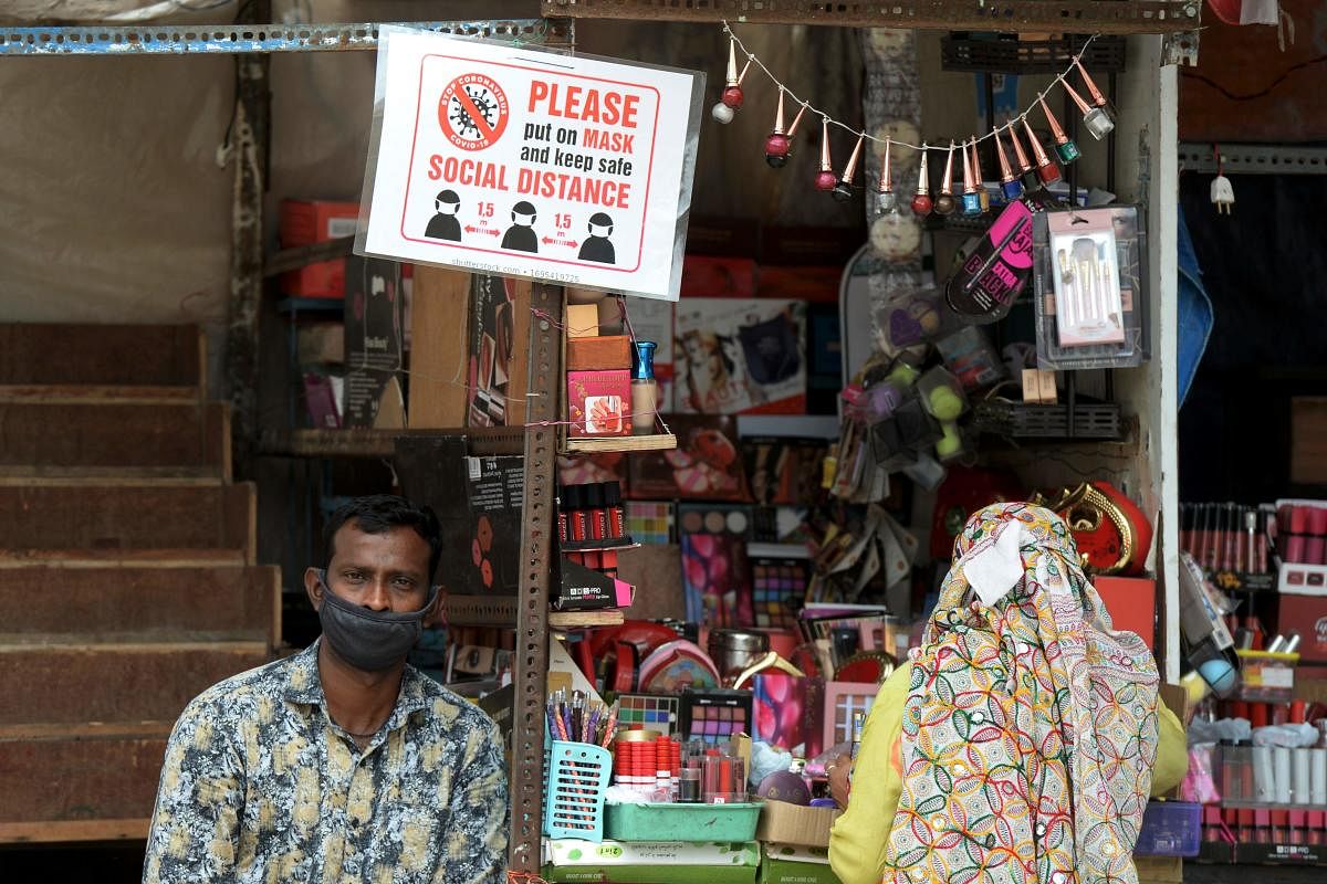 A sales man (L) displays a notice board waiting for customers beside Charminar historic monument as it reopened after the government eased a nationwide lockdown imposed as a preventive measure against the spread of coronavirus, in Hyderabad on July 7, 2020. Credit: AFP Photo