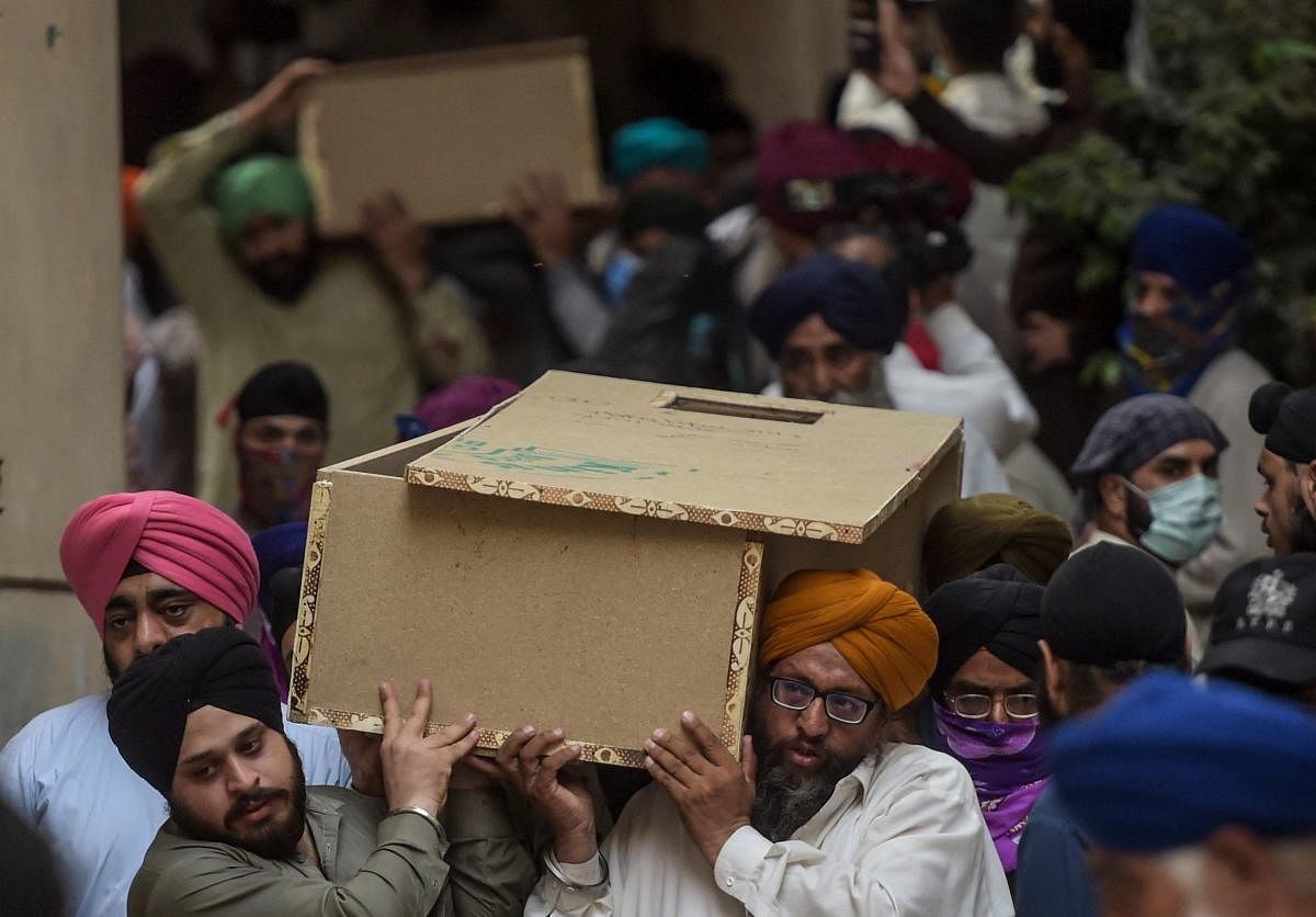 Sikhs carry the coffins of relatives during a funeral ceremony in Peshawar on July 4, 2020, who died in an accident between a train and the van transporting Sikh pilgrims.(AFP Photo)
