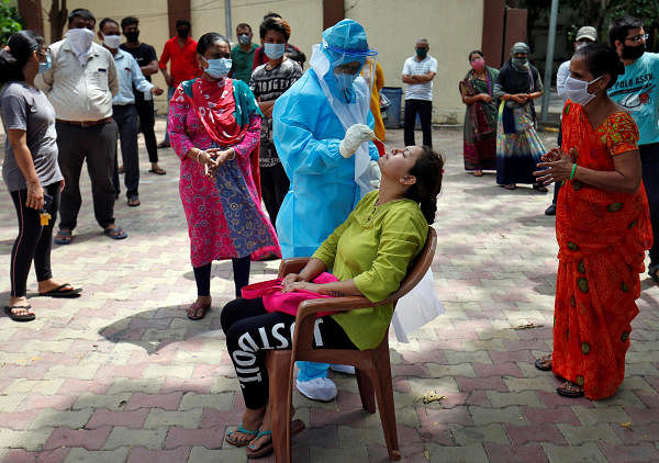 A healthcare worker wearing Personal Protective Equipment (PPE) takes swab from a woman to test for the coronavirus disease at a residential area in Ahmedabad, India, July 8, 2020. Credit: Reuters Photo