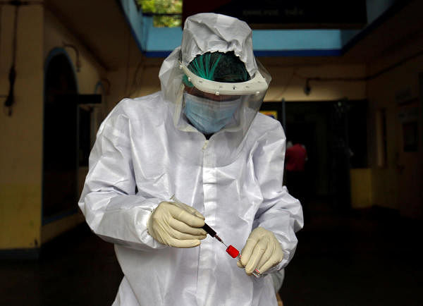 A healthcare worker wearing a protective gear transfers blood sample of a resident into a vial during a check-up campaign to tackle the coronavirus disease outbreak in Ahmedabad, India, July 6, 2020. Credit: Reuters Photo