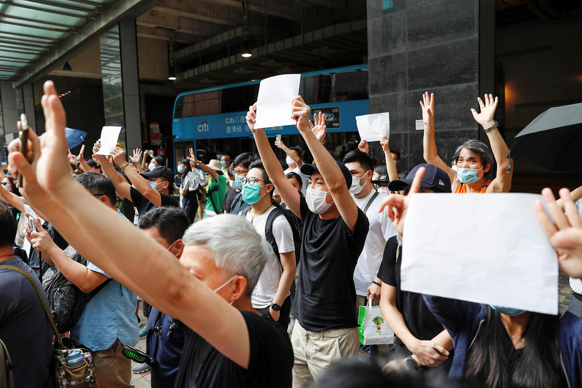 Supporters raise white paper to avoid slogans banned under the national security law as they support arrested anti-law protester outside Eastern court in Hong Kong, China. Credit: Reuters
