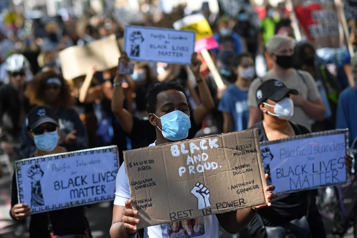 Protesters wearing protective face coverings hold placards as they march down Park Lane in support of the Black Lives Matter movement. Credit: AFP