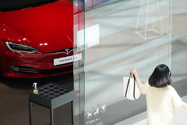 A woman walks past a Tesla dealership. Credit: Reuters