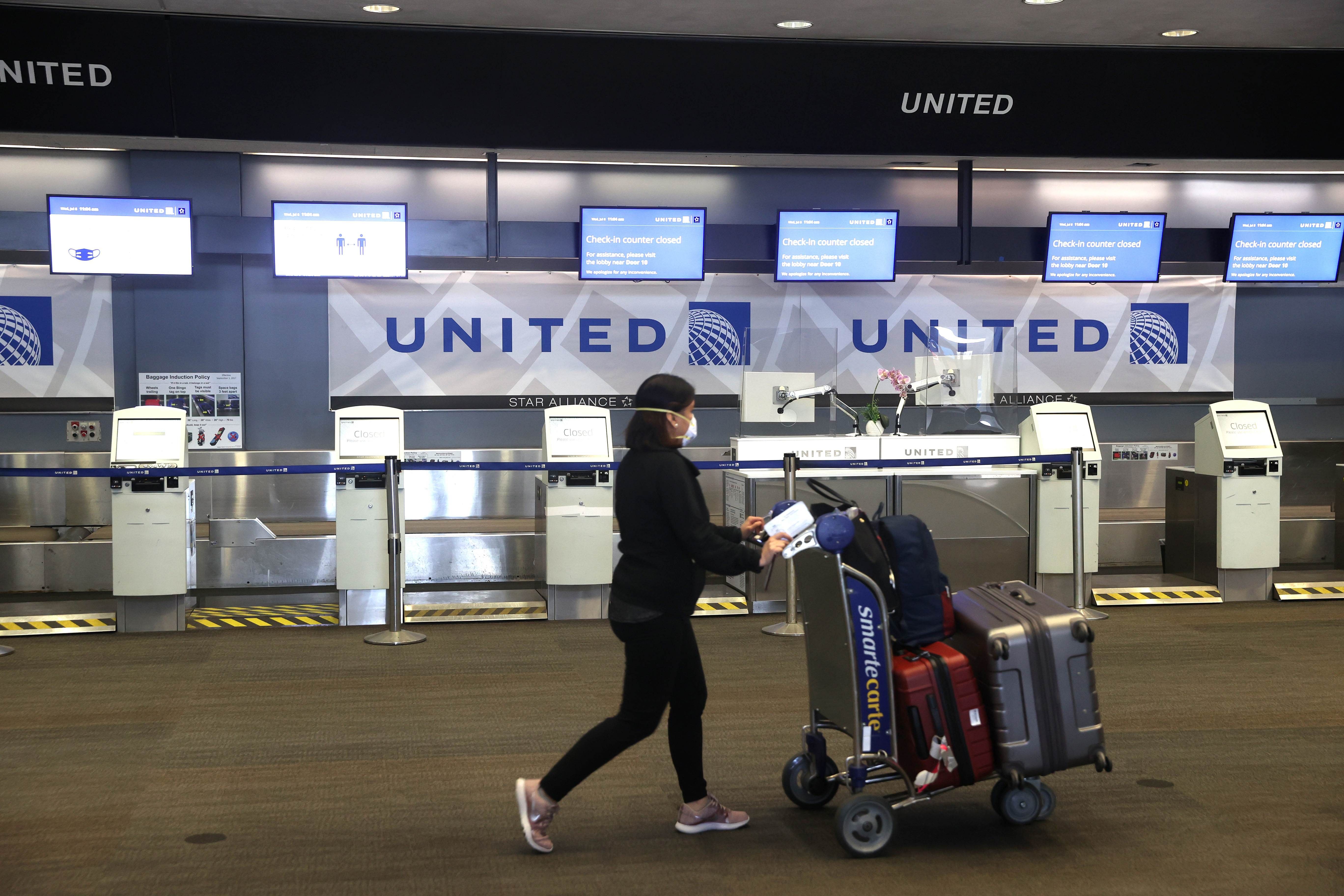A United Airlines passenger pushes a luggage cart past closed check-in kiosks at San Francisco International Airport. Credits: AFP Photo