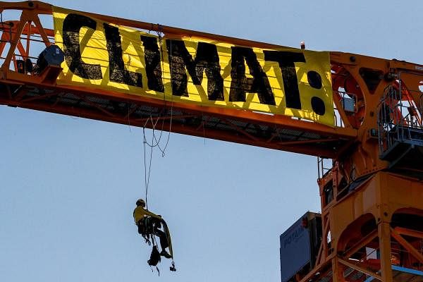 A Greenpeace activist hangs, on a crane, a giant banner reading "Climate" during a protest against the French government's politics on environment, on the work site of Notre-Dame Cathedral, in Paris. Credit: AFP