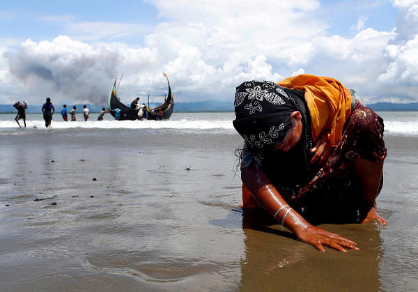 An exhausted Rohingya refugee woman touches the shore after crossing the Bangladesh-Myanmar border by boat through the Bay of Bengal in Shah Porir Dwip, Bangladesh, September 11, 2017. Credit: Reuters Photo