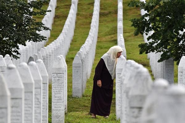 Bosnian Muslim woman Mejra Djogaz, 71, survivor of Srebrenica 1995 massacre, kisses her sons' tombstones, Omer, 19, and Munib, 21, her two sons killed in the massive killing of Srebrenica during Bosnia's 1992-95 war, at Potocari memorial center, near Srebrenica on July 3, 2020. Credit: AFP Photo