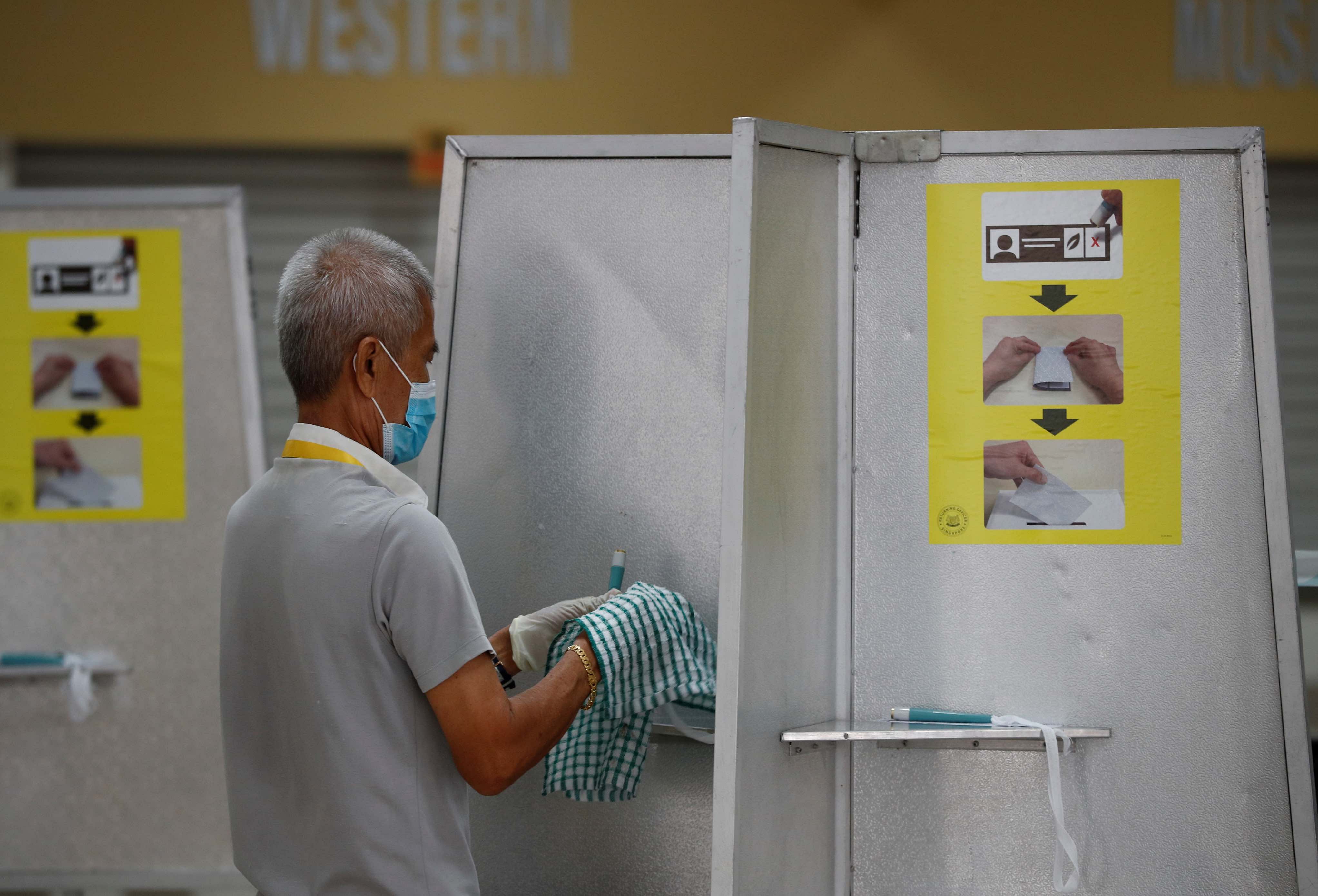 An electoral personnel sanitises self-inking pens at a ballot booth at a polling station. Credit: Reuters