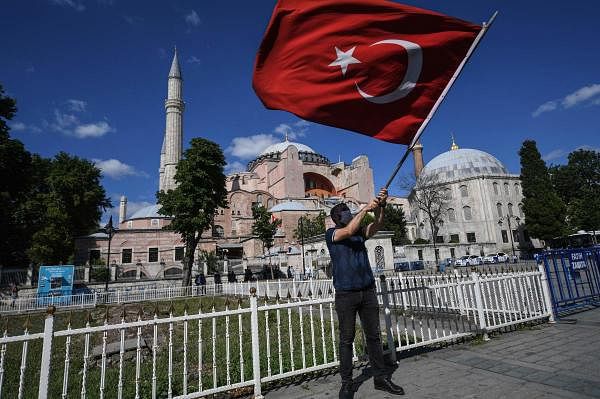 A man waves a Turkish national flag as people gather outside the Hagia Sophia museum on July 10, 2020 in Istanbul to celebrate after a top Turkish court revoked the sixth-century Hagia Sophia's status as a museum, clearing the way for it to be turned back into a mosque. Credit: AFP Photo