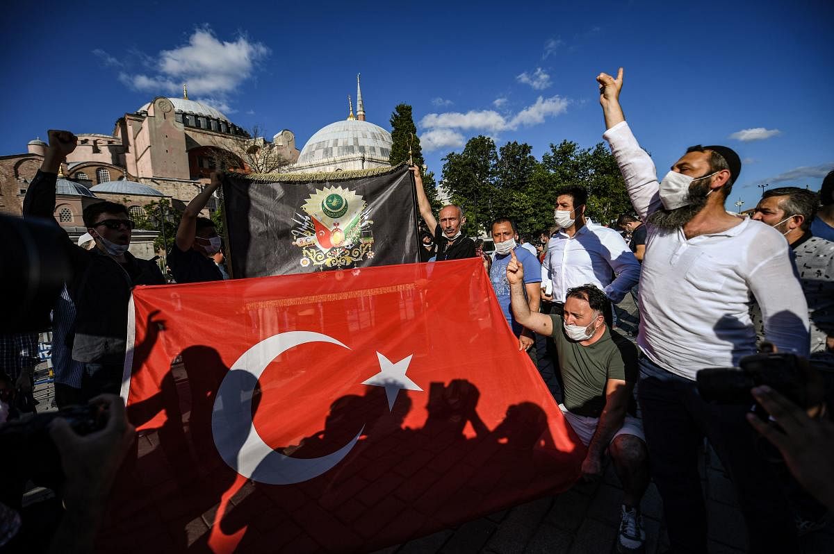  People waves a Turkish national flag (front) and a flag with the Turkey Coat of arms of the Ottoman Empire Tughra, as they celebrate outside the Hagia Sophia museum (AFP Photo)