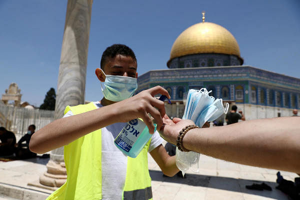 A youth offers a sanitation liquid to a worshipper to fight the spread of the coronavirus disease after Friday prayer next to al-Aqsa mosque on the compound known to Muslims as the Noble Sanctuary and to Jews as the Temple Mount, in Jerusalem's Old City July 10, 2020. Credit: Reuters Photo