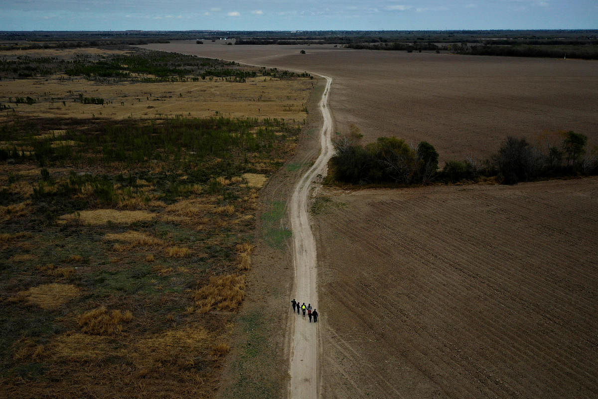 A group of migrants walk past plowed farmland after crossing into the United States from Mexico. Credit: Reuters file photo