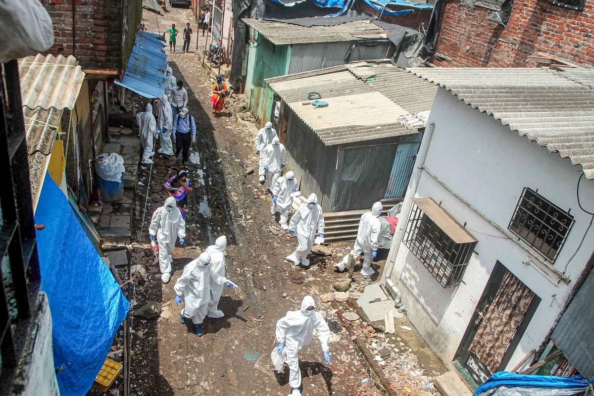 Health workers wearing PPE suits arrive to conduct screening of the residents in a COVID-19 containment zone in Ambujwadi area, in Mumbai. Credit: PTI Photo