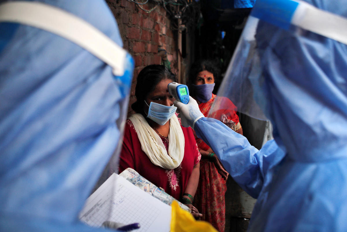 A healthcare worker checks the temperature of a woman using an electronic thermometer during a check up campaign for the coronavirus disease (COVID-19) at a slum area in Mumbai, India July 8, 2020. REUTERS/Francis Mascarenhas